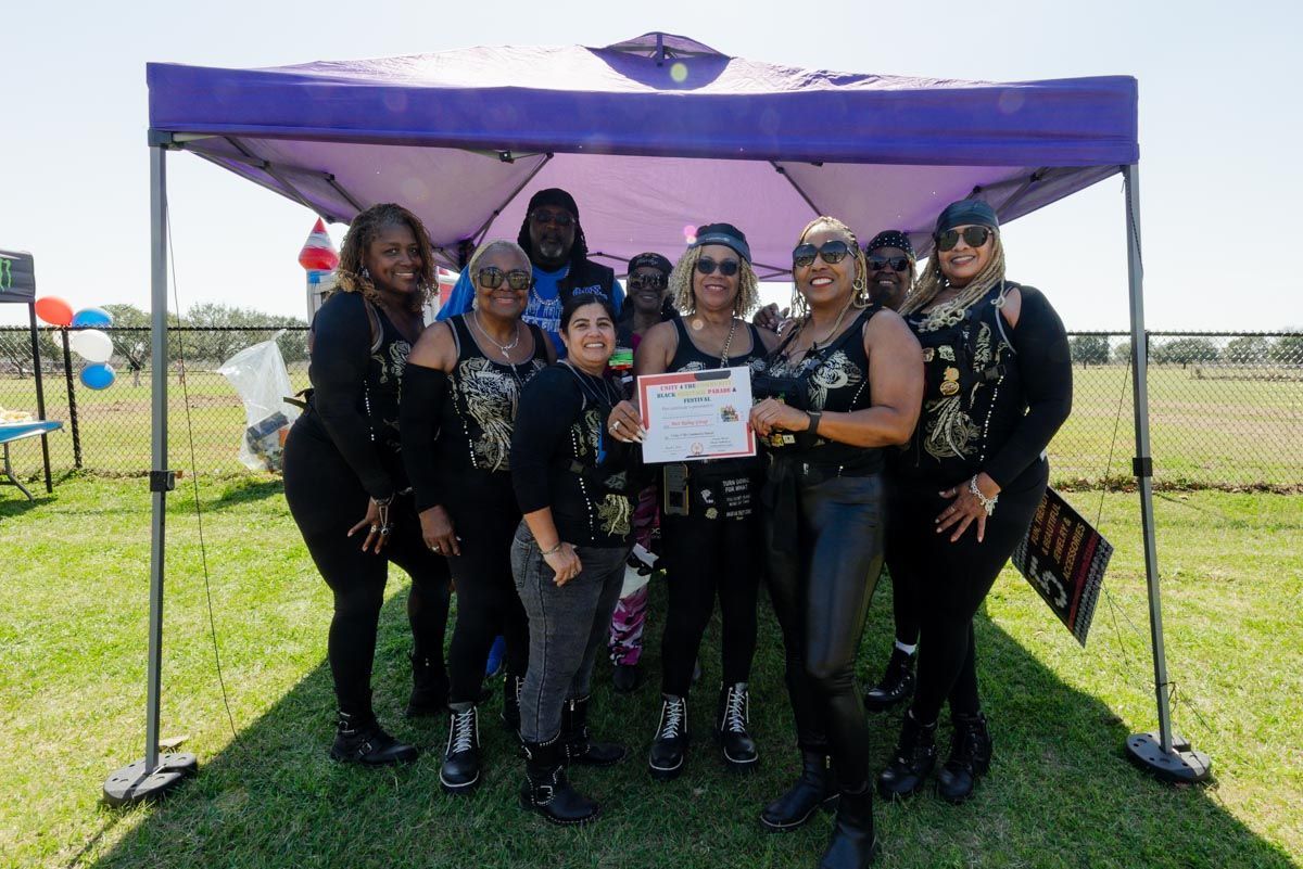 A group of women are posing for a picture under a purple tent.