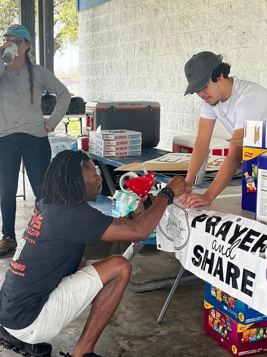A man kneeling in front of a sign that says prayer and share