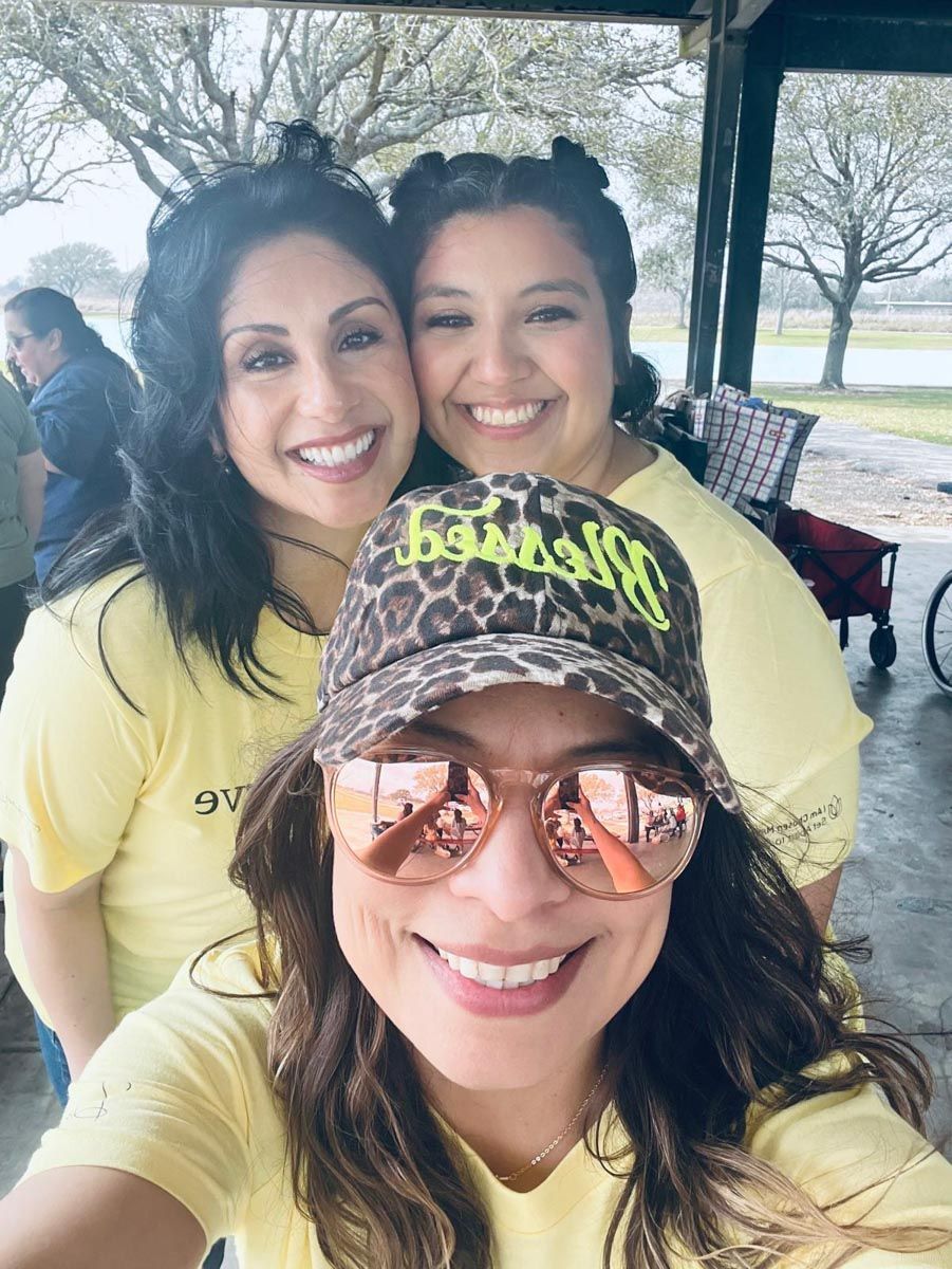 Three women are posing for a picture and one of them is wearing a leopard print hat.