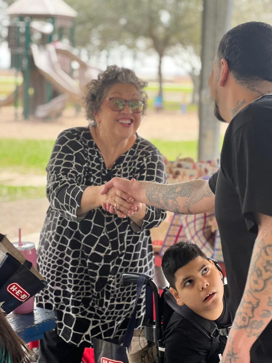 A woman in a giraffe print shirt shakes hands with a man in a black shirt