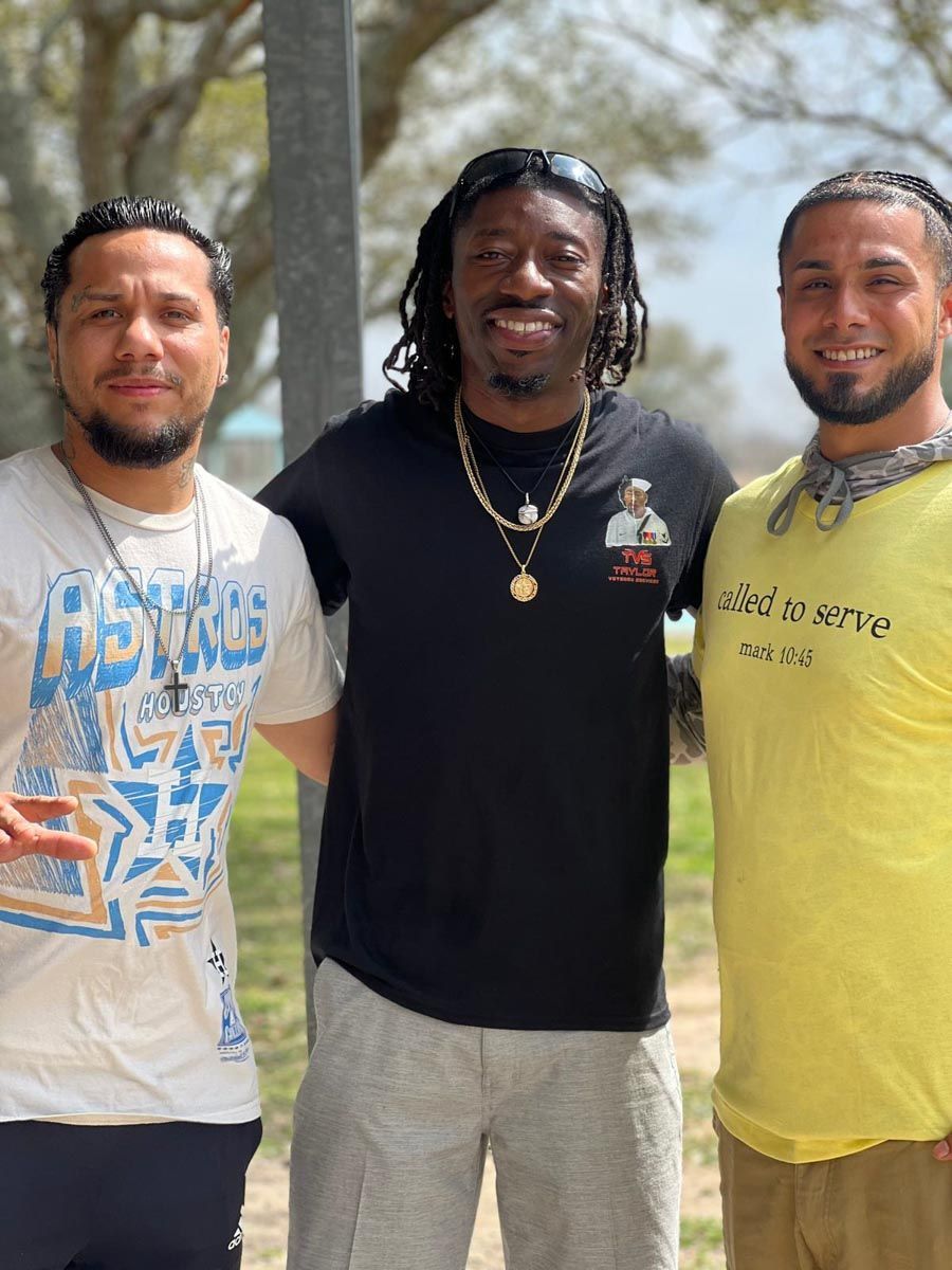 Three men posing for a picture with one wearing a yellow shirt that says called to serve