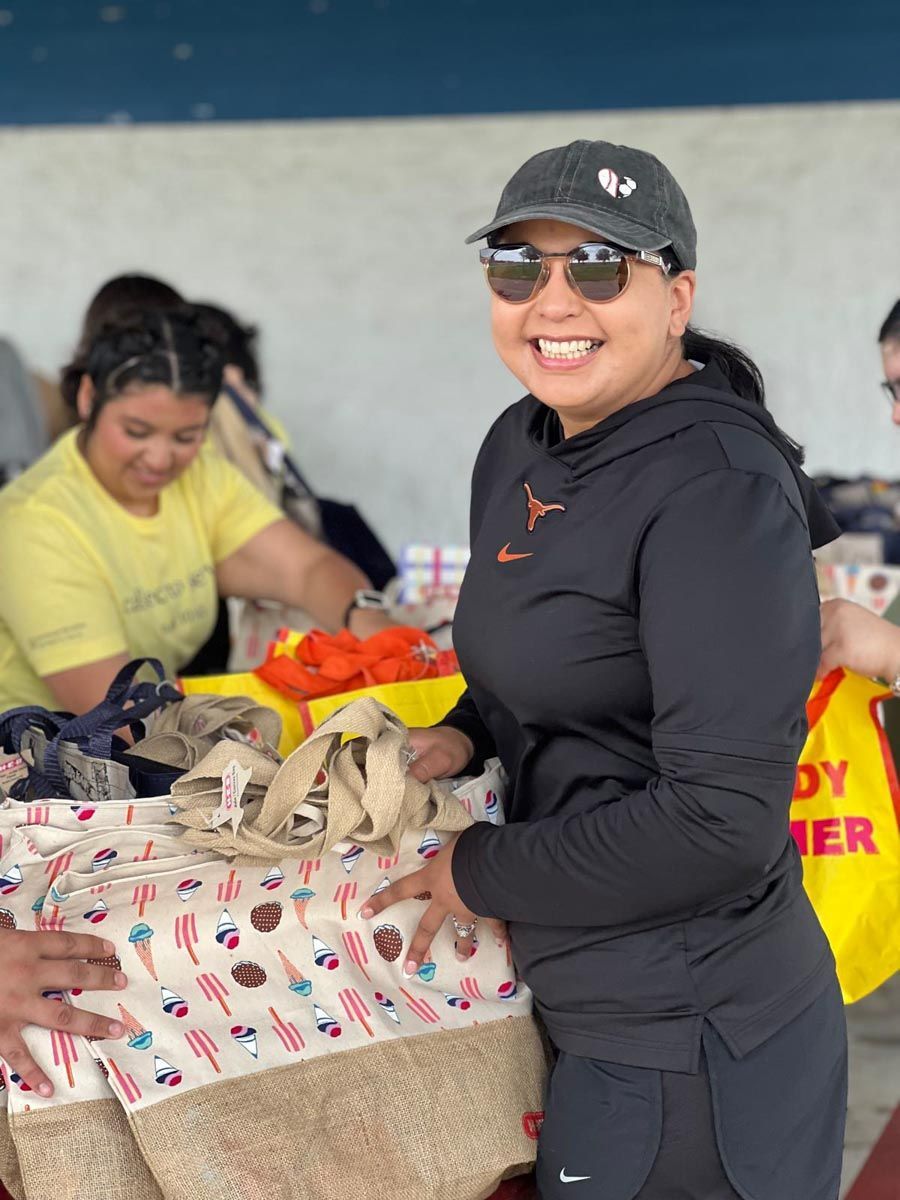 A woman wearing sunglasses and a hat is standing in front of a table.