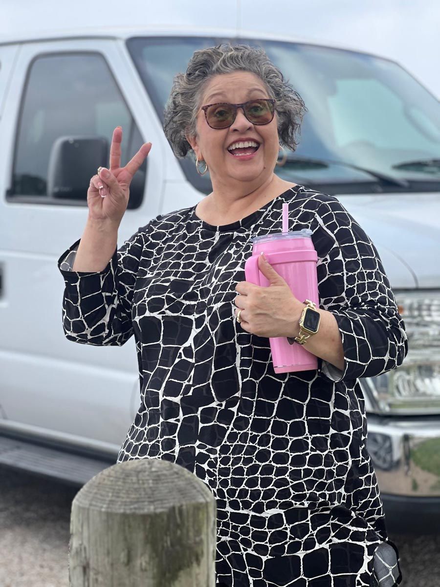 A woman standing in front of a van giving a peace sign
