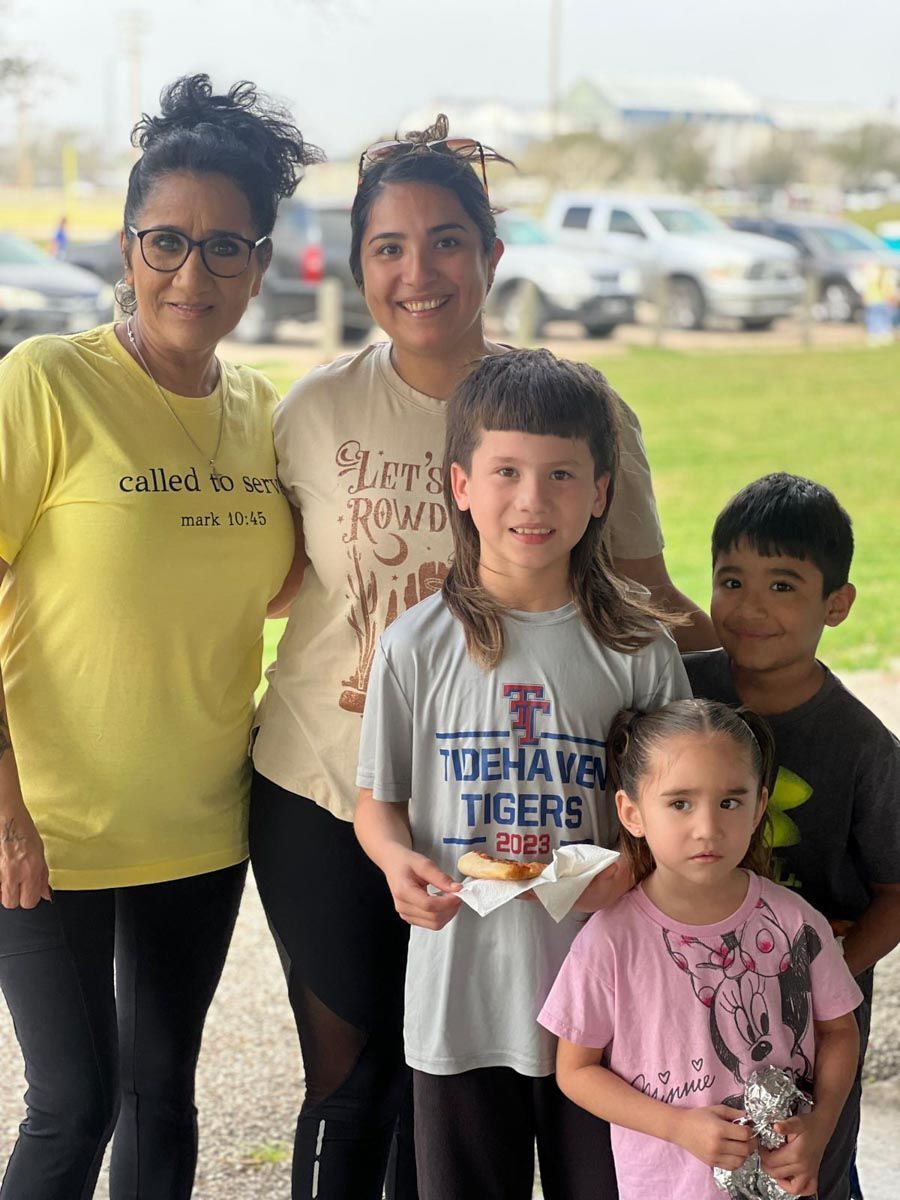A group of people posing for a picture with one girl wearing a shirt that says tigers