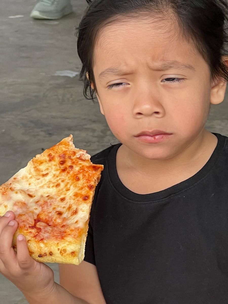 A little girl is holding a slice of pizza in her hand