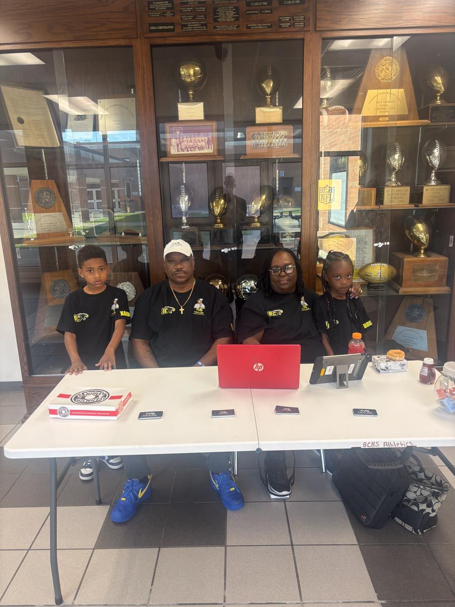 A group of people sitting at a table with a laptop on it