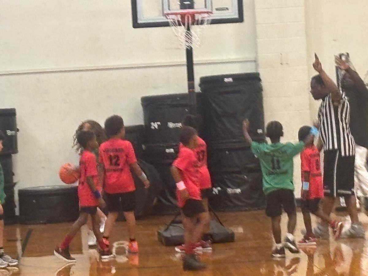 A group of kids are playing basketball and one of them has the number 12 on their shirt