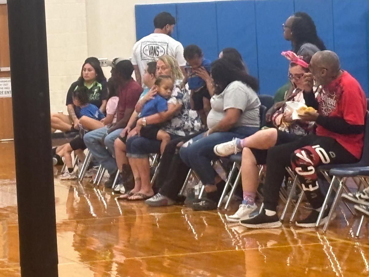 A group of people are sitting in chairs in a gym