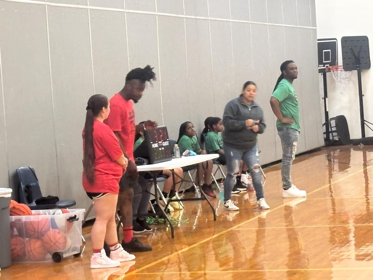 A group of people are watching a basketball game in a gym.