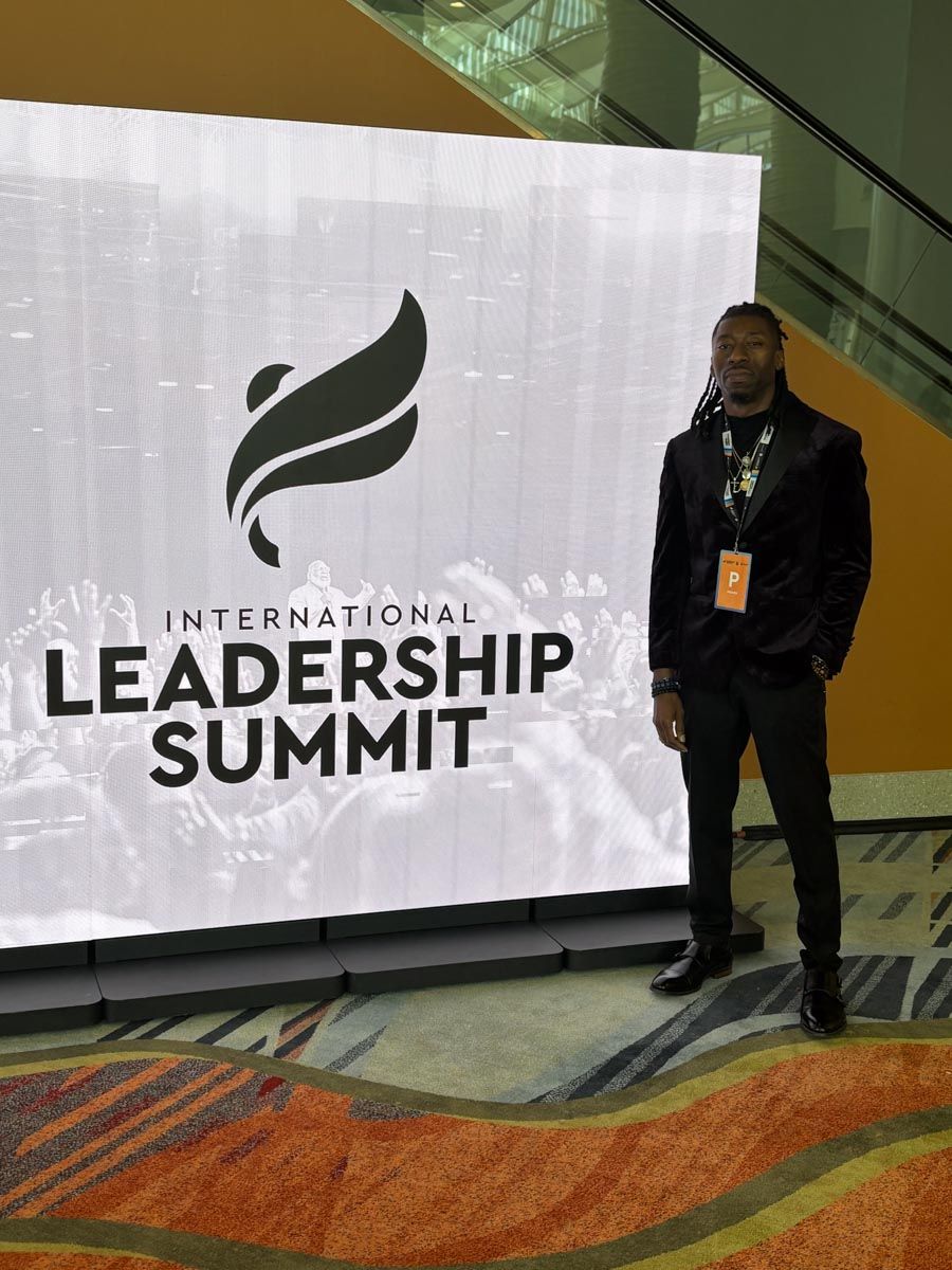 A man standing in front of a sign that says international leadership summit