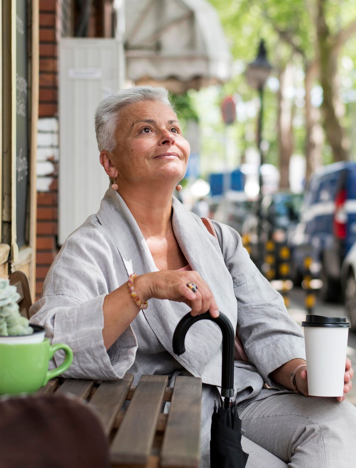 A dirt road going through a field with trees on both sides.