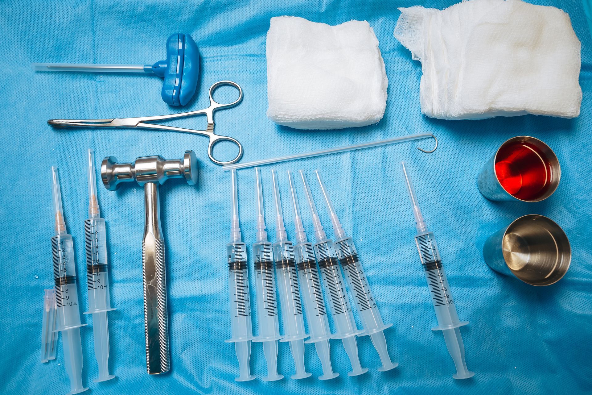 A bunch of syringes and surgical instruments on a blue cloth
