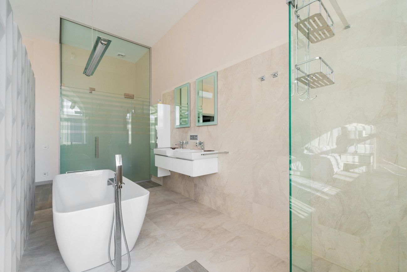 Fresh white bathroom tiled with large format porcelain tiles in Swansea by Daffodil Tiling.