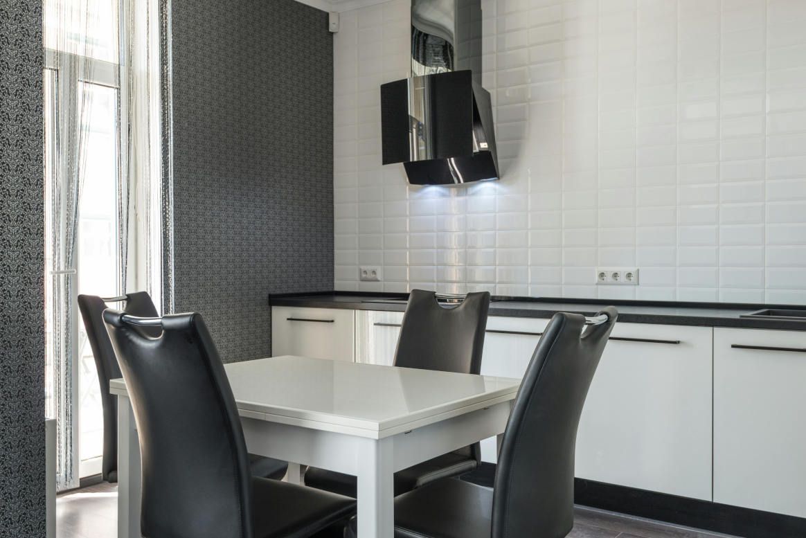Modern kitchen with a white table, black chairs, and white cabinets.