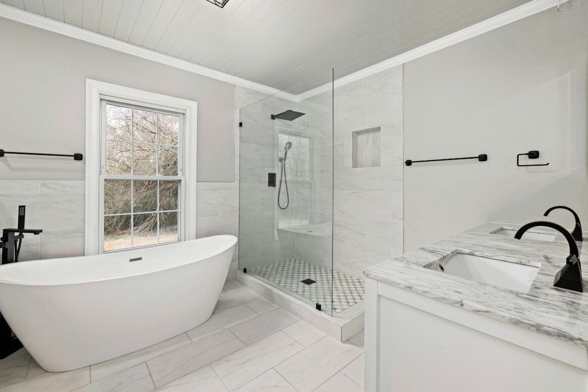 Modern white bathroom with a freestanding tub, glass shower, and double vanity.