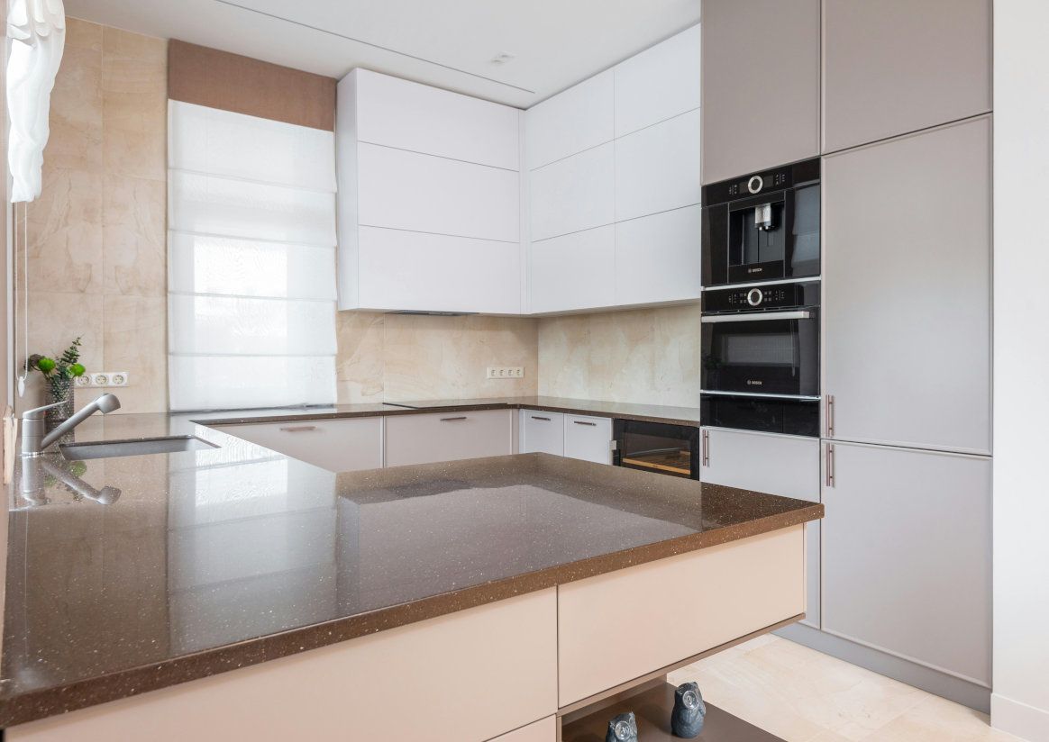 Modern kitchen with brown countertops, white and gray cabinets, and built-in appliances.