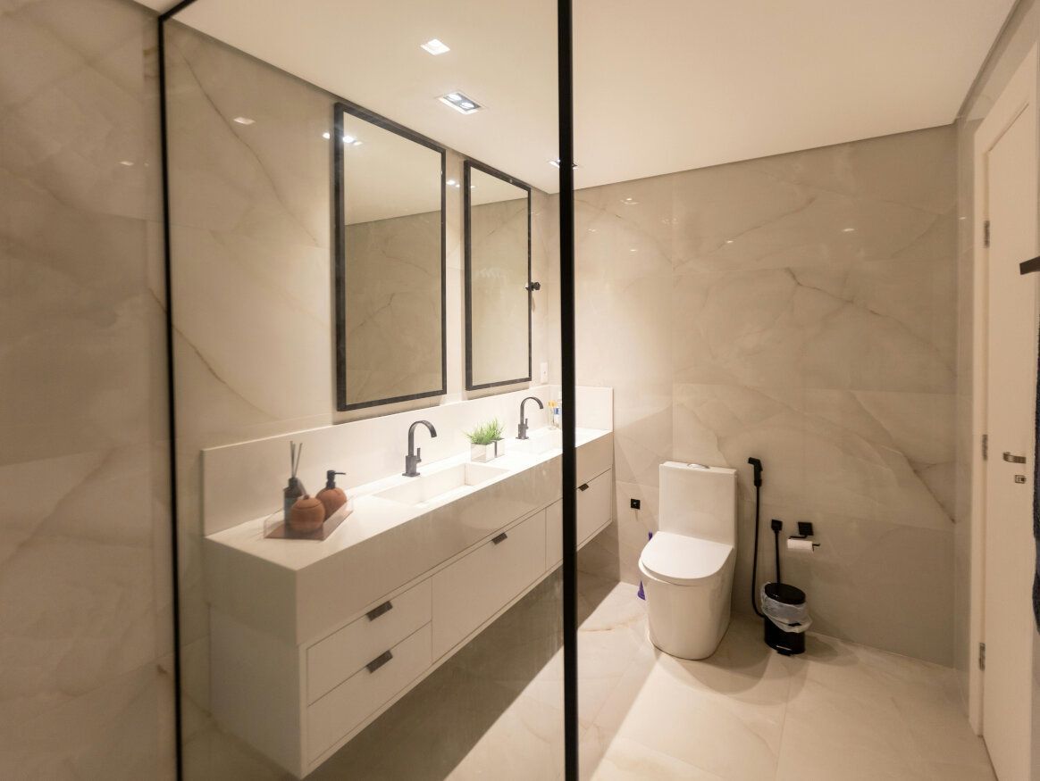 Modern white bathroom with a floating vanity, two mirrors, and a toilet.