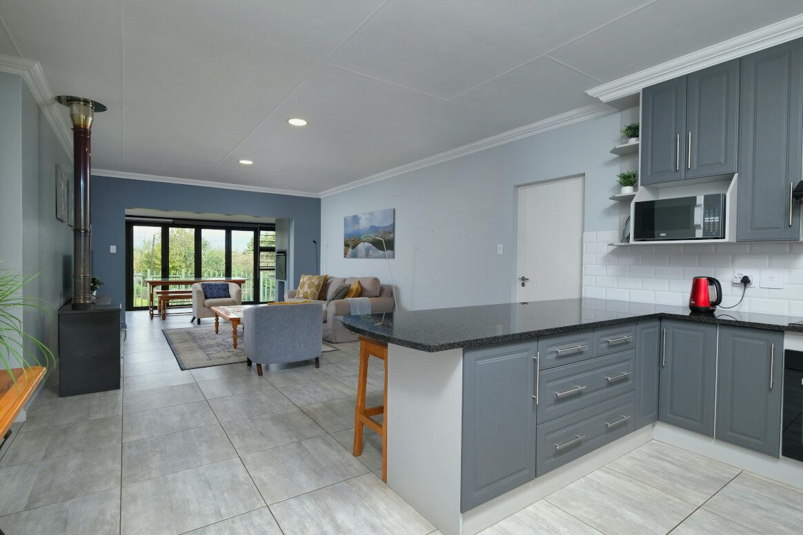 Open-plan kitchen and living room with gray cabinets, black countertops, and a view to a patio.