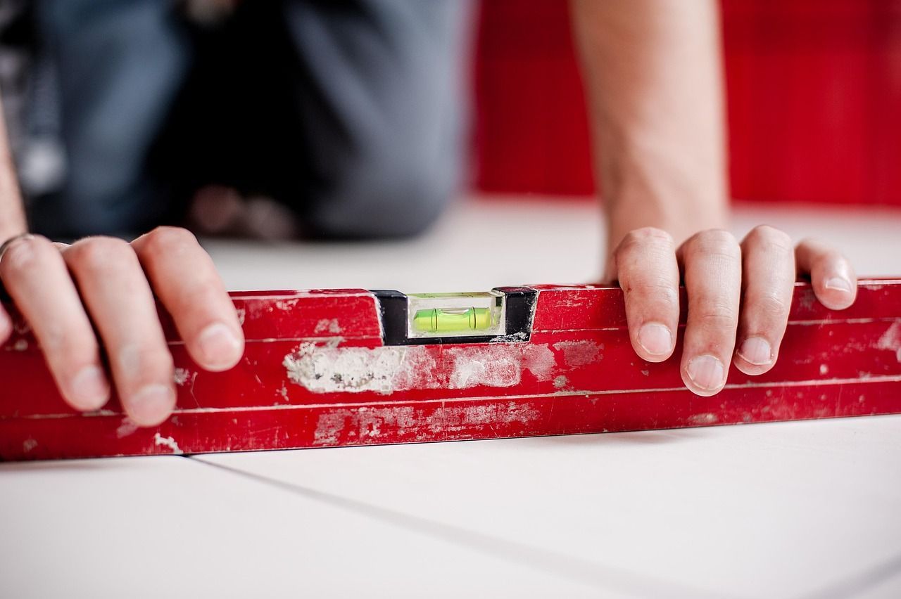 Person using a red level to check the flatness of a white surface, likely during construction.