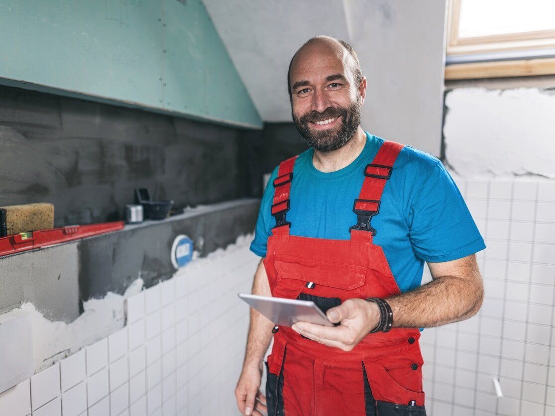 Professional Swansea bathroom tiler, smiling, completing a wall tiling project by Daffodil Tiling.