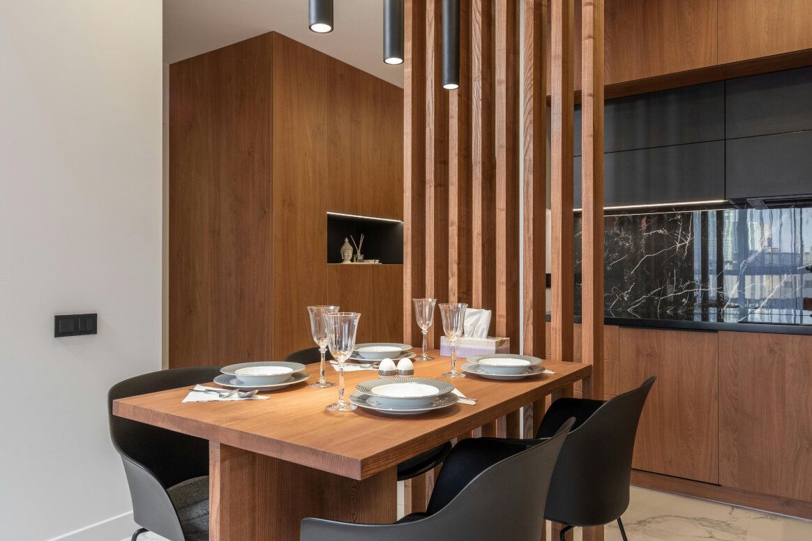 Dining area with wooden table, four black chairs, and a slatted wooden divider.