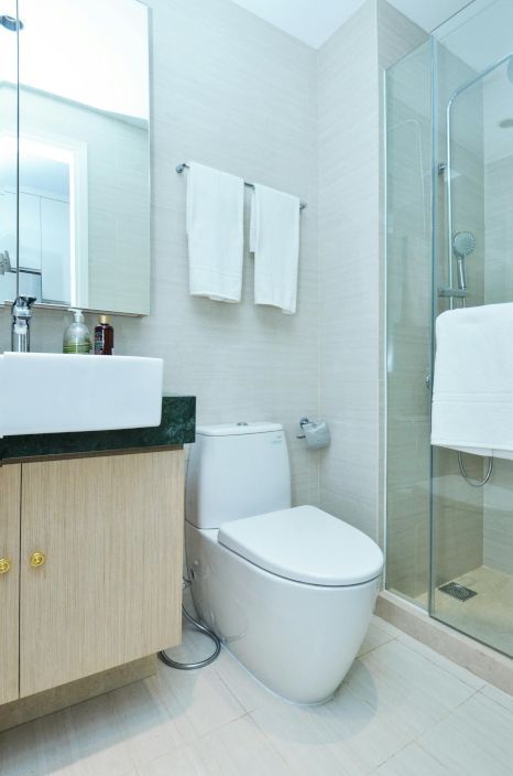 A bathroom with a toilet a sink and a shower. Expertly tiled by Daffodil Tiling in Swansea, Wales.