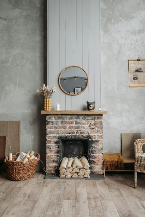 A living room with a brick fireplace and a basket of logs.