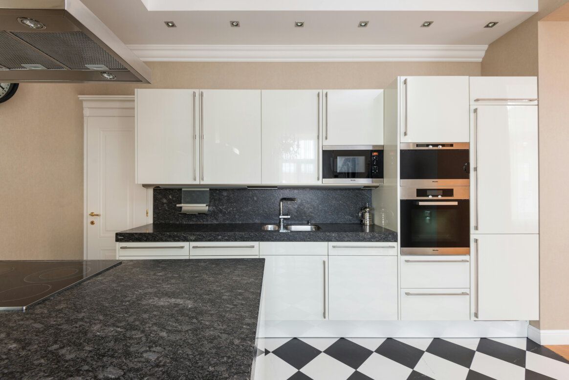 Modern white kitchen with black countertops and a checkered floor.