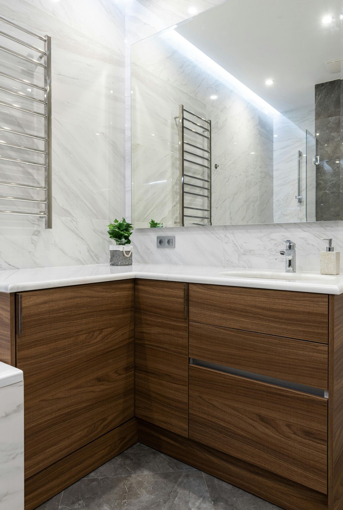 Modern bathroom with dark wood vanity, marble countertop, and large mirror.