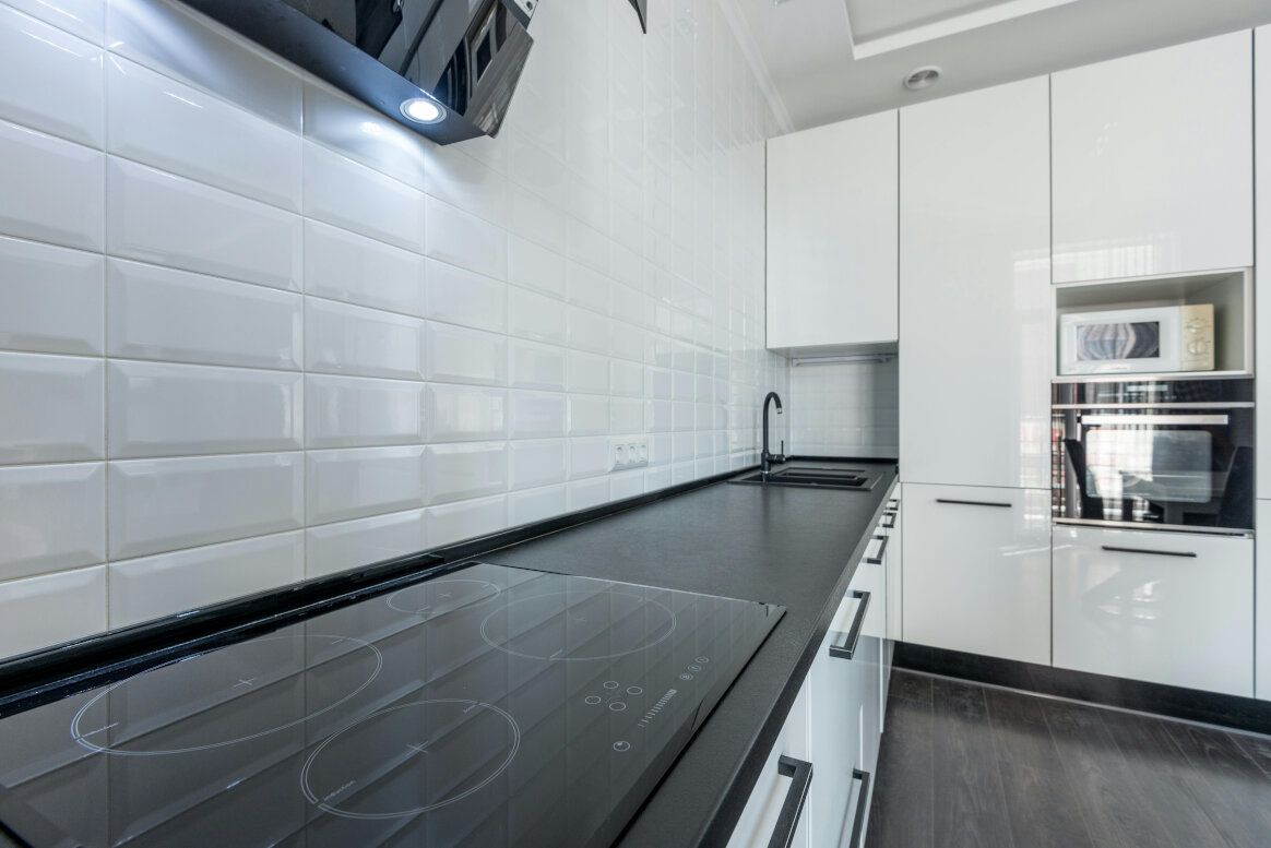 Modern kitchen with black countertops, white cabinets, and appliances.