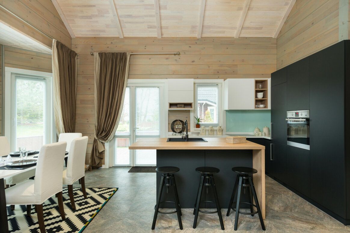 Modern kitchen with dark island, black stools, and white dining chairs.
