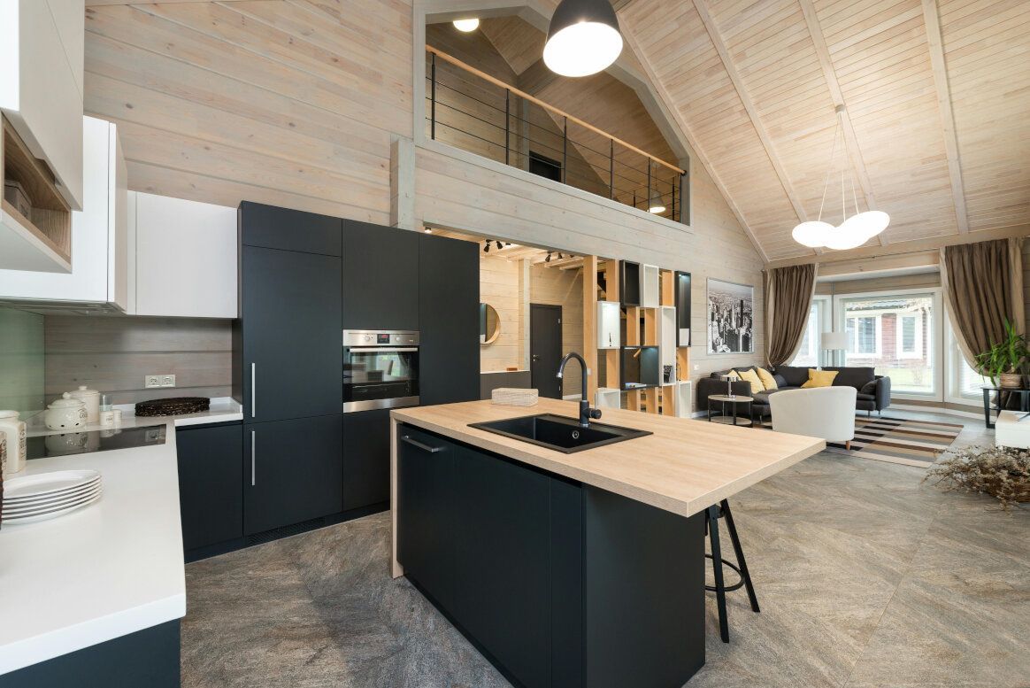 Modern open-plan kitchen and living area with wooden beams, black cabinets, and an island.