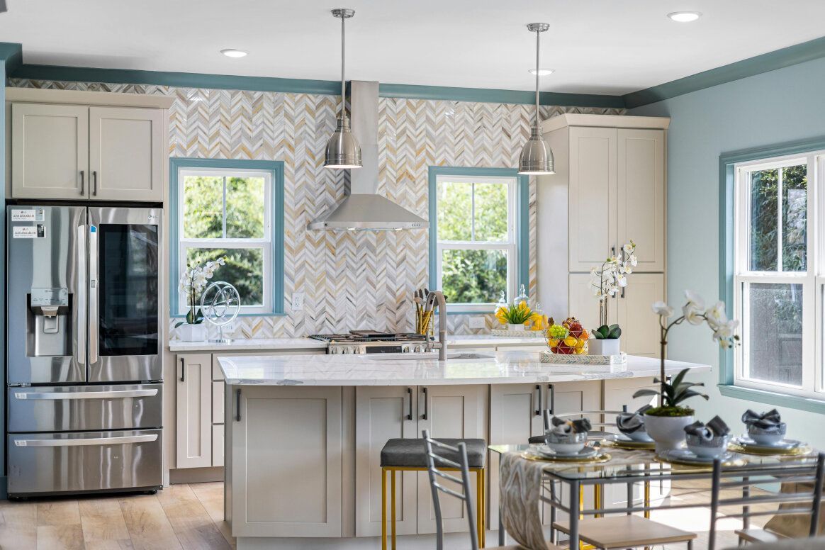 Modern kitchen with light blue walls, white cabinets, stainless steel appliances, and a central island.