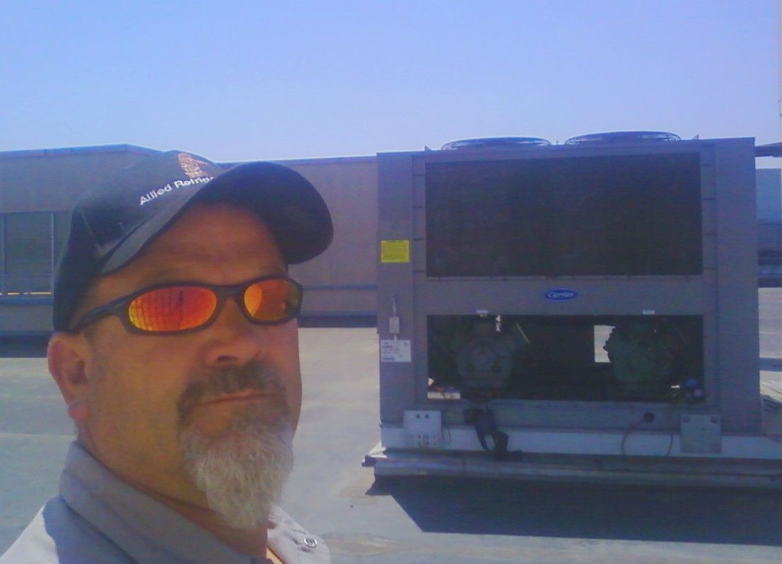 A man wearing sunglasses and a hat is standing in front of a large machine