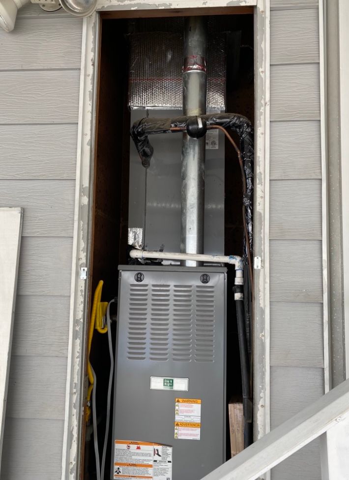 An air conditioner is sitting inside of a doorway on the side of a building.