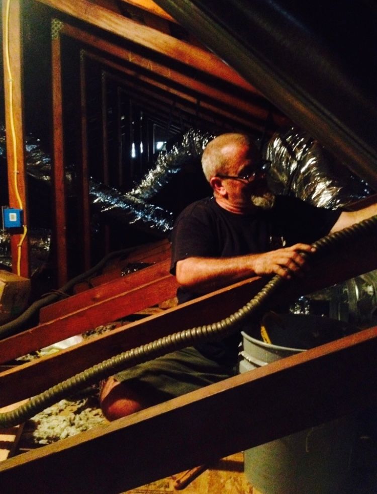 A man is working in an attic with a hose