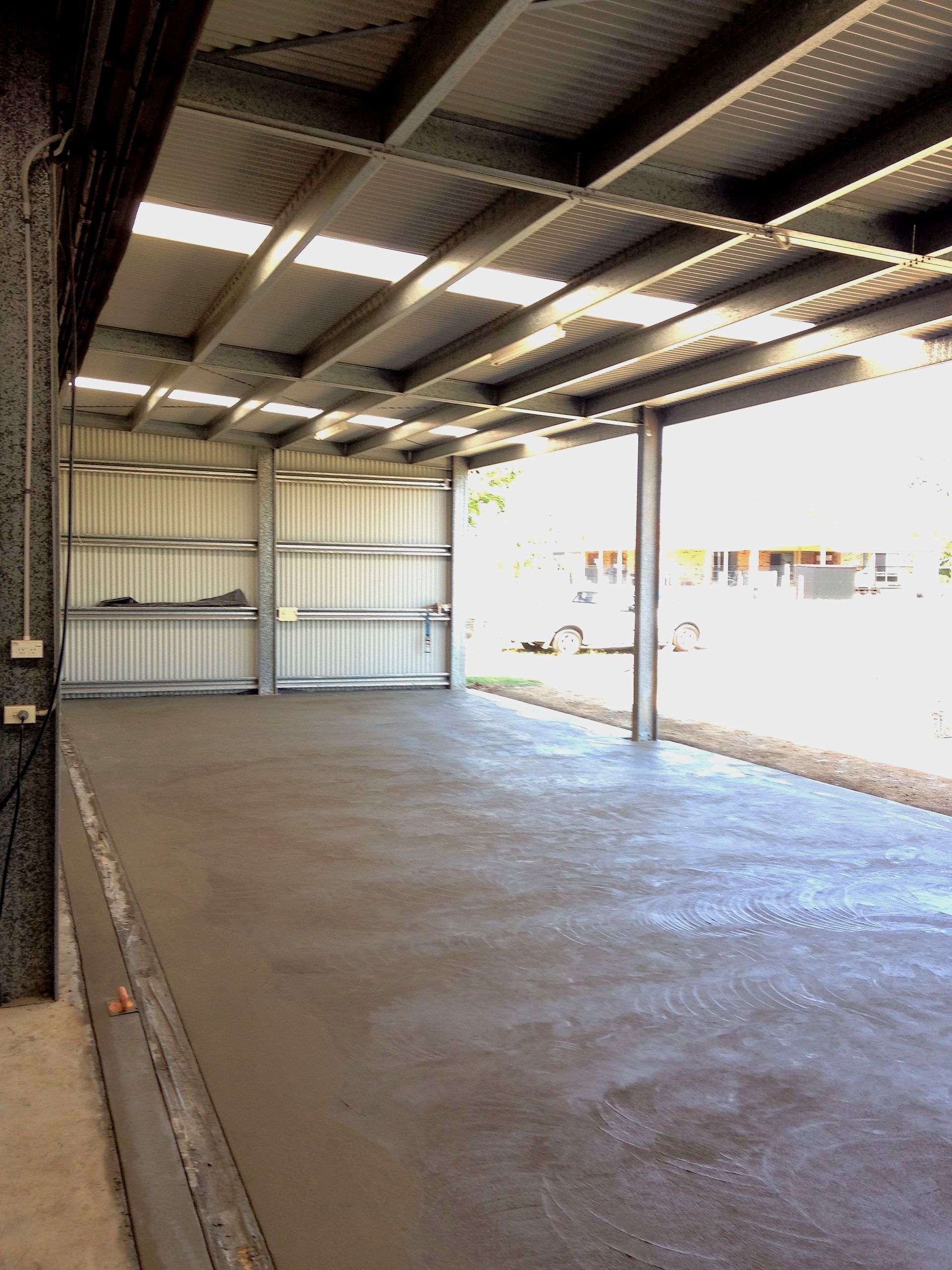 A large empty warehouse with a concrete floor and a metal roof.   — Showcase Concrete & Polishing in Bundaberg South, QLD