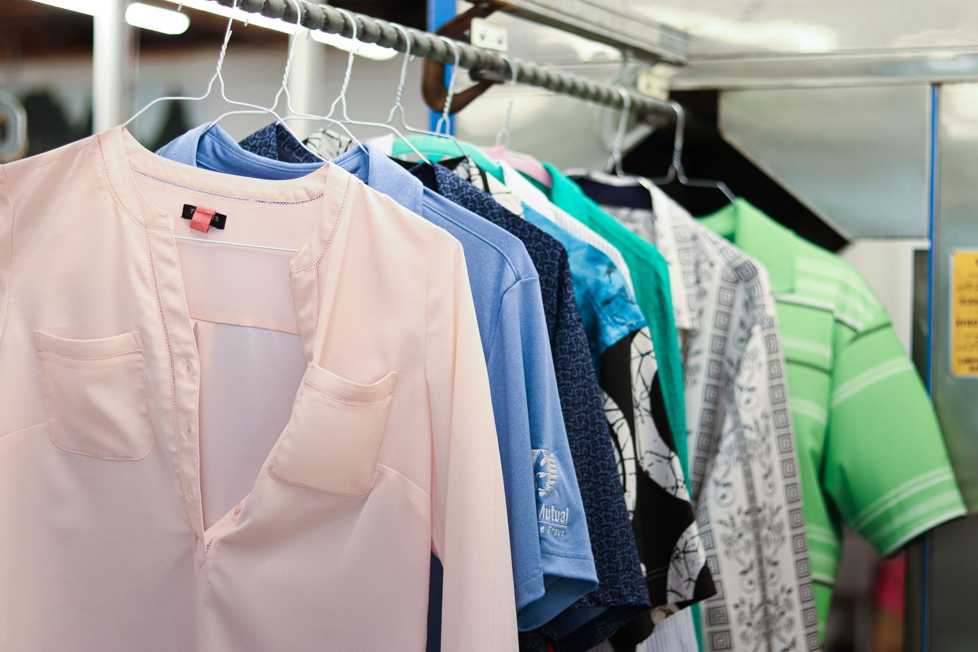 Shirts hanging on a rack; various colors including pink, blue, and green.