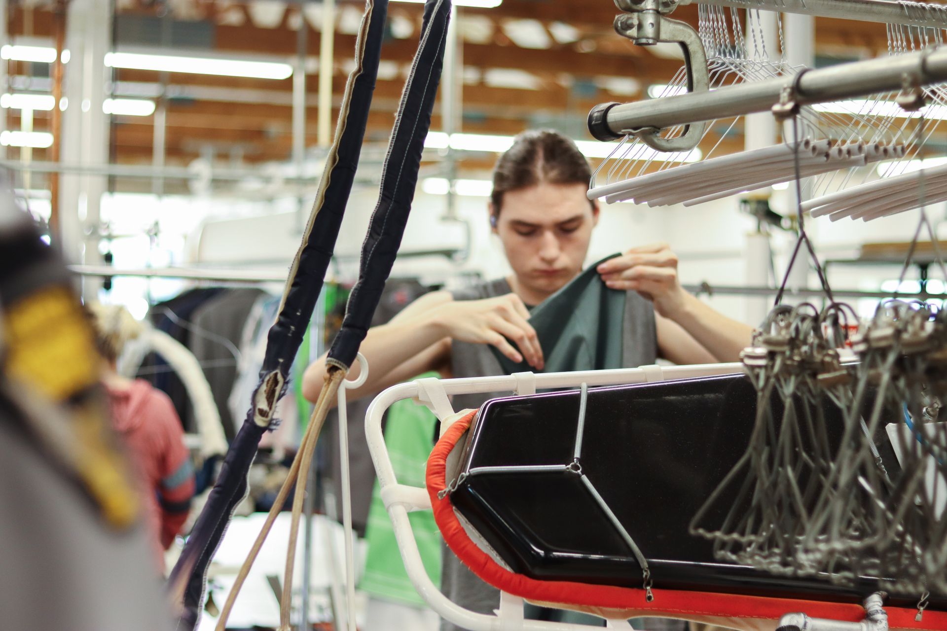 A young person inspecting fabric on a machine in a factory setting.
