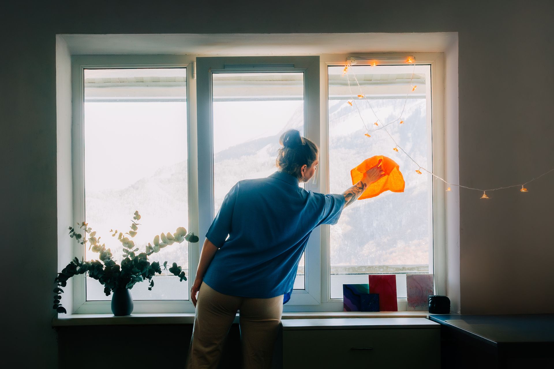 Woman cleaning windows in bright apartment using cloth.