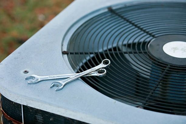 Two wrenches on top of an air conditioning unit.