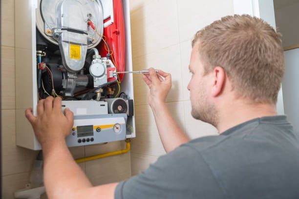 Man repairing a wall-mounted boiler with a screwdriver. White boiler cabinet with yellow gas pipe.