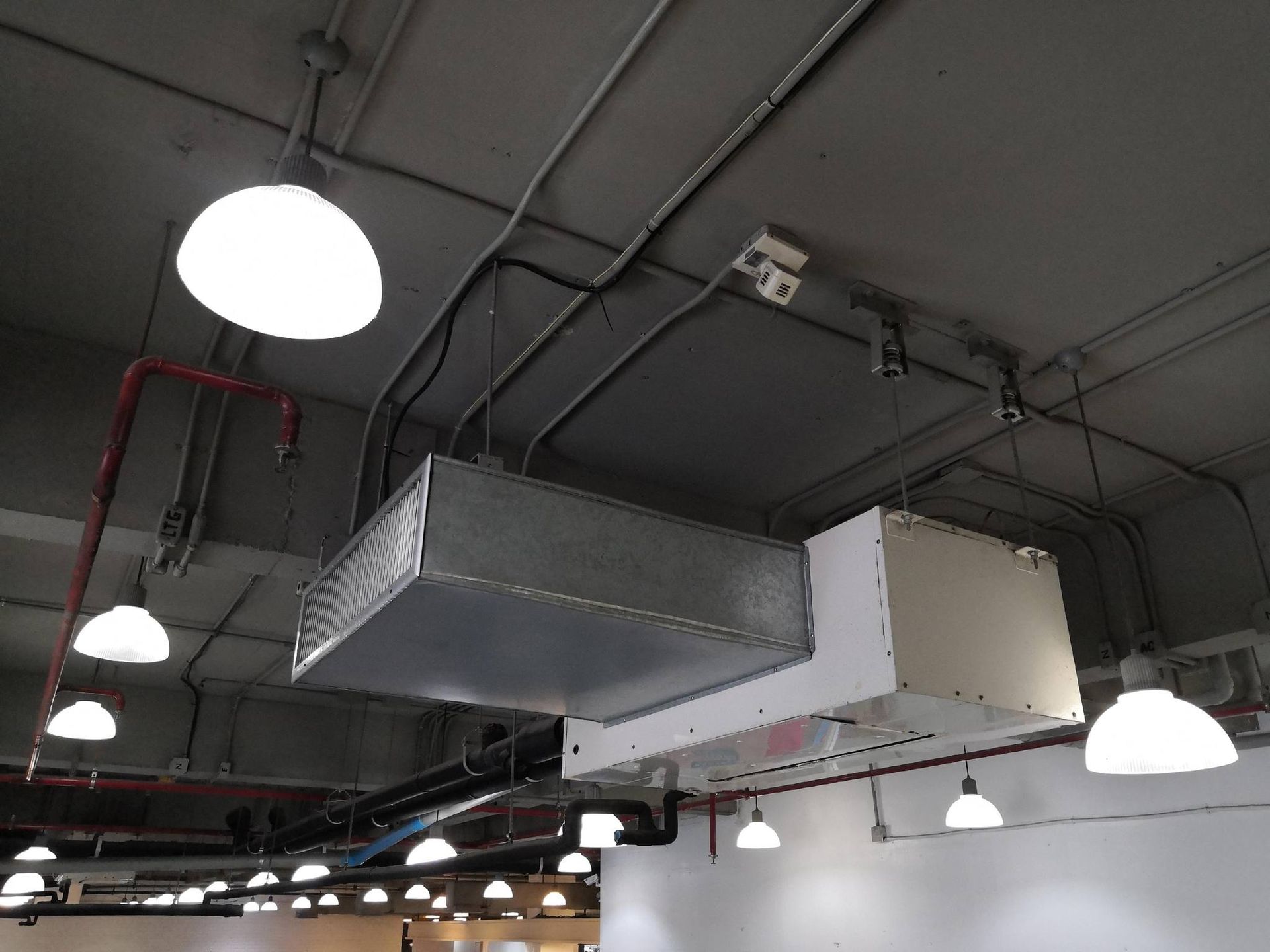 Ceiling with ductwork, lights, and a white rectangular HVAC unit.