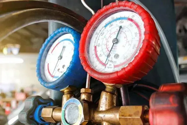 Close-up of blue and red gauges connected to brass fittings. They are used for measuring pressure.