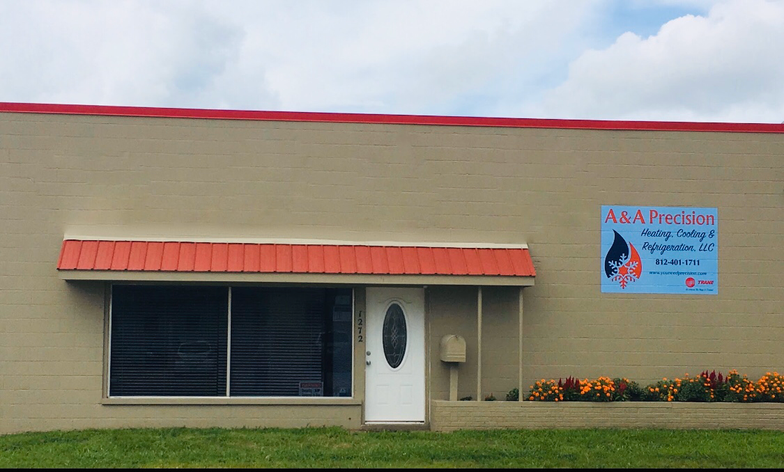 Tan building with red trim, awning, and sign for 