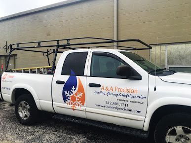 White A&A Precision service truck with logo and ladder rack, parked in front of a building.