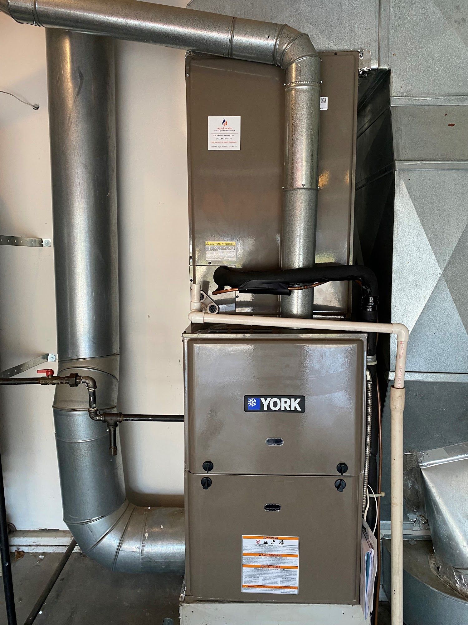 A York furnace and air handler unit with ductwork in a utility room.