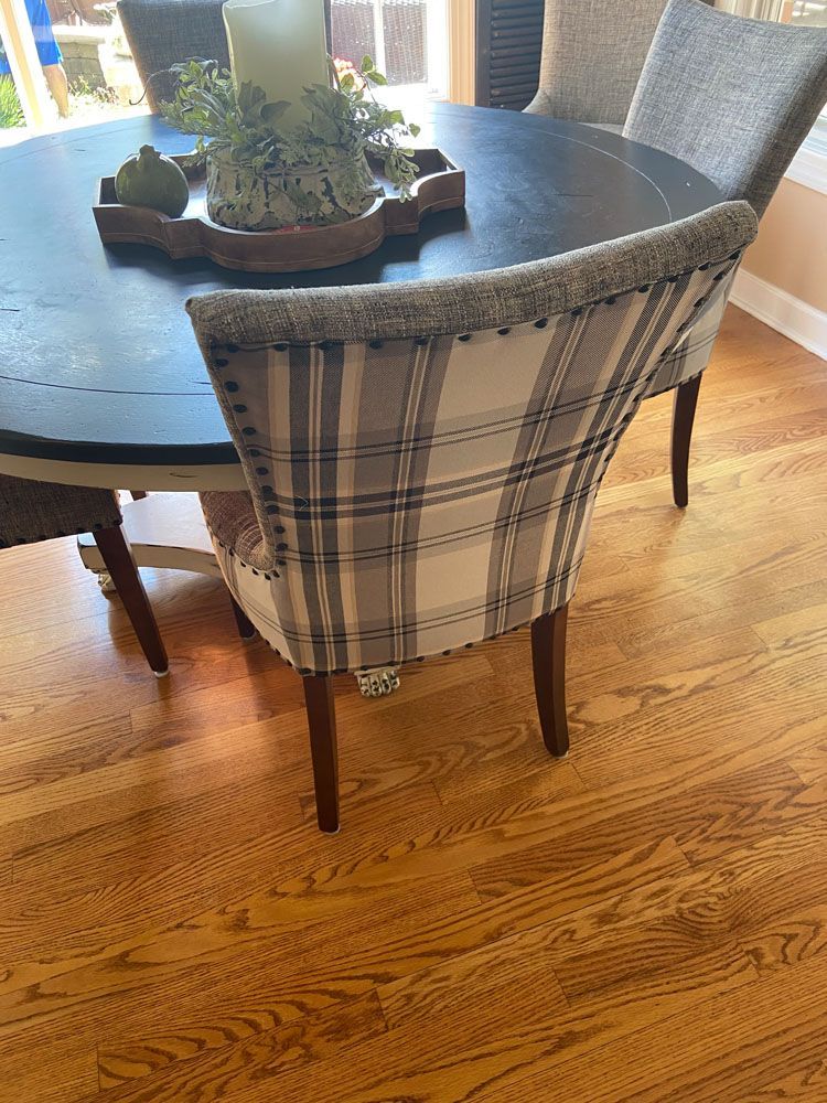 Dining room with plaid chairs around a dark round table, hardwood floor.