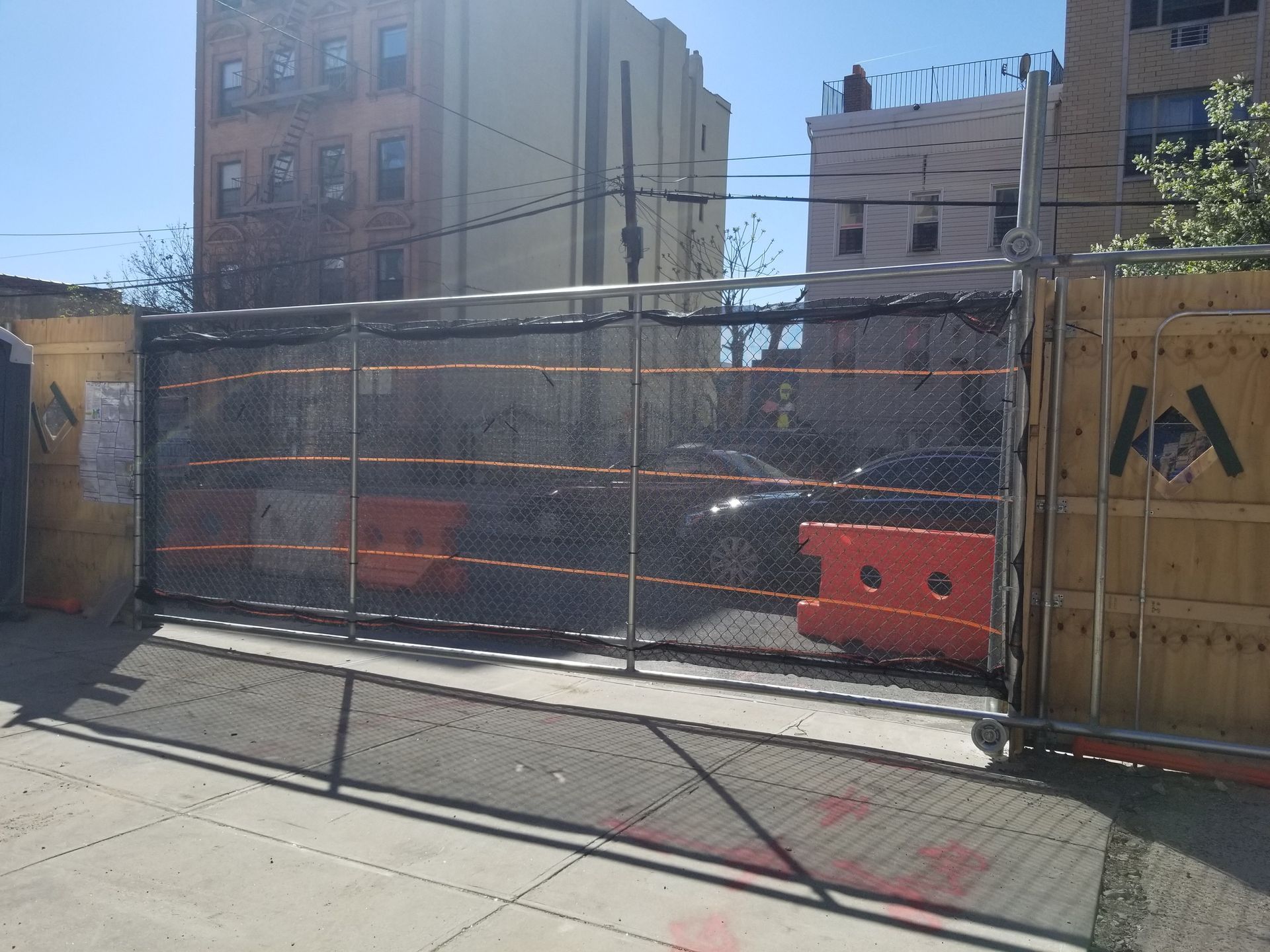 Construction site fenced in, with orange traffic barriers visible.
