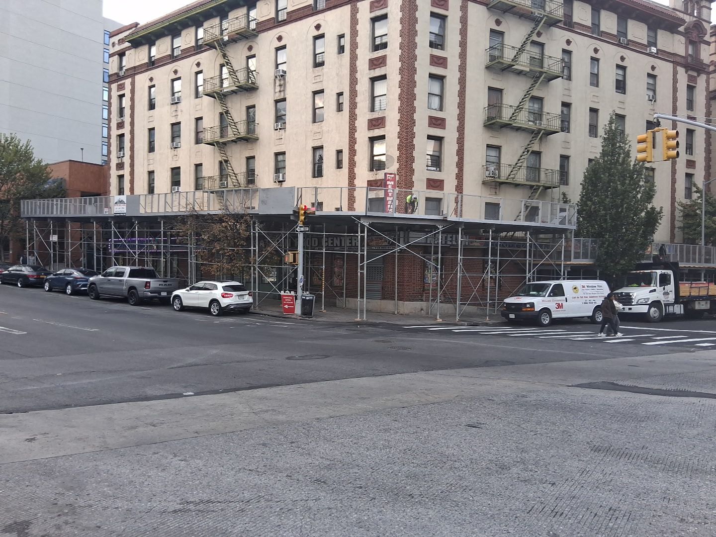 Scaffolding outside a brick building, covering the sidewalk.